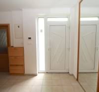 The entrance hall of a family house with white doors, a mirror, and a wooden shoe cabinet.
