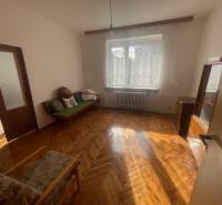 Wooden parquet in a bright room of a family house with a sofa and an armchair.