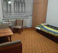 A room in a family house with a bed, wardrobe, table, and chairs, decorated in warm colors.