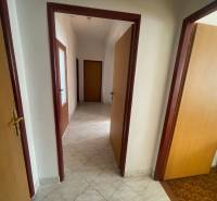 Interior of a family house with a hallway, doors, and light tiles.