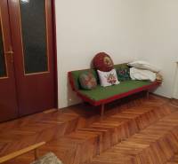 Interior of a family house with a wooden floor, a sofa, and cushions in the corner of the room.