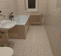 A bathroom in a family house with a bathtub, sink, toilet, and radiator on the wall.