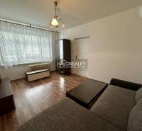 Living room in a one-room apartment with a window, curtains, dark furniture, and a sofa.