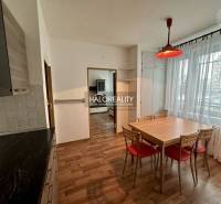 Dining room in a one-bedroom apartment with wooden floors and a large window with lace curtains.