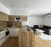 Living room and kitchen in a 3-room apartment with wooden flooring and furniture.