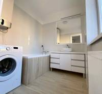 A bathroom in a 3-room apartment with a bathtub, a washing machine, and a cabinet under the sink.