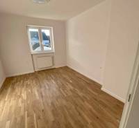 A room in a 3-room apartment with a wooden floor and white walls, a window with a view.