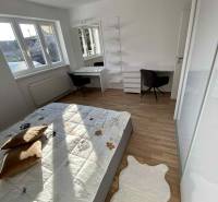 A bedroom in a 3-room apartment with light furniture, a bed, and a workspace.
