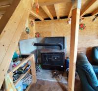 Interior with wooden stairs, a comfortable armchair, and a traditional stove. Property - housing.