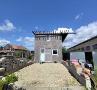 Building plot in Jelšovce suitable for living, with a garden house in the background.