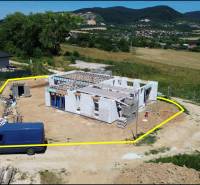 A family house construction in Trenčianske Jastrabie, surrounded by greenery and hills.