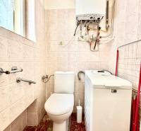 Bathroom in a 2-room apartment with a toilet, washing machine, and gas boiler on the wall.