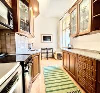 A kitchen in a 2-room apartment with wooden cabinets, a stove, and a spacious countertop.