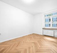A room in a 3-room apartment with wooden flooring and a large window.