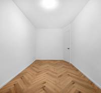 An empty room with white walls and wooden flooring in a 3-room apartment.