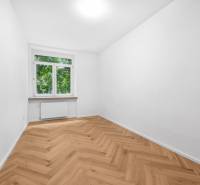 A room in a 3-room apartment with a parquet floor and a large window, light decoration.