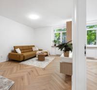 Living room in a three-room apartment with a brown sofa and wooden floor.