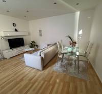 Living room with a sofa, television, and glass table in a two-room apartment.
