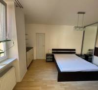 Bedroom in a 2-room apartment with a bed, wardrobe, and a large window with a flower.