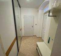 A hallway in a 2-room apartment with a built-in wardrobe and a bench, neutral design.