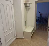 Entrance hallway of a 2-room apartment with white furniture and tiles.