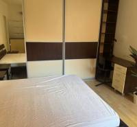 Bedroom in a two-room apartment with a bed, desk, and wardrobe.
