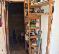 A small room with a storage rack, a shovel, and gardening tools. Premises - living.