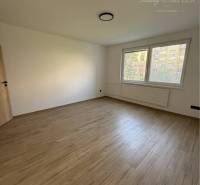 A room with a wooden floor and a large window in a 3-room apartment.