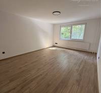 A spacious room with a wooden floor and a large window in a 3-room apartment.