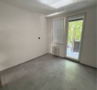 A room with large windows and light tiles in a 3-room apartment.