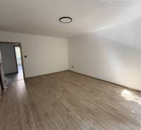 A room with a wooden floor in a 3-room apartment, with one window and an entrance door.