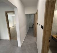A hallway in a 3-room apartment with wooden doors and ceramic tiles.