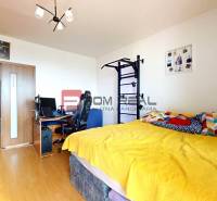 A bedroom with a computer and a yellow bed in a 3-room apartment, with decorations on the wall.