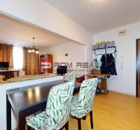 Interior of a 3-room apartment with a dining table, wooden doors, and shelves on the wall.