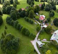 Aerial view of recreational plots in Oščadnica surrounded by dense greenery and houses.