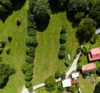 Aerial view of recreational plots in Oščadnica with greenery, buildings, and a road.