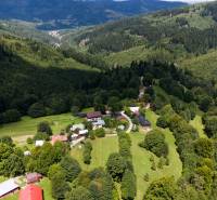 Aerial view of wooded recreational lands in Oščadnica with rural buildings.