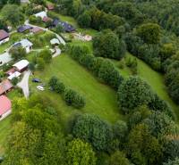 Aerial view of recreational plots in Oščadnica, surrounded by forests and houses.