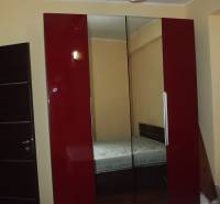 A wardrobe with red doors and a mirror in a 3-room apartment with a bedroom.