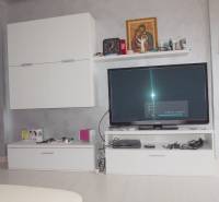 Furnishing in a 3-room apartment with white cabinets and a television on a gray painted wall.