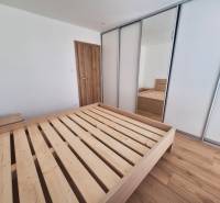 Bedroom with a wooden bed and a built-in wardrobe in a 2-room apartment.