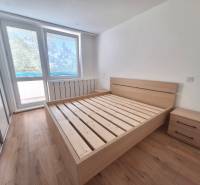 A bright bedroom with a wooden bed and nightstands in a two-room apartment.