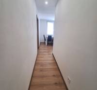 A hallway in a 2-room apartment with wooden flooring and ceiling lights.