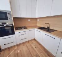 A kitchen in a 2-room apartment with wooden flooring and built-in appliances.