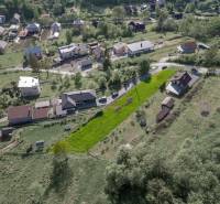 An aerial view of residential plots in the village of Raková, green slopes and houses.