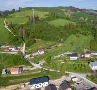 Aerial view of residential plots in Raková, surrounded by green hills and houses.