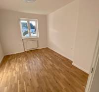 A room in a 3-room apartment with a wooden floor and a large window.