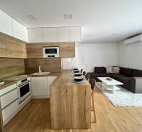 A kitchen connected to the living room in a 3-room apartment, with wooden details and seating.