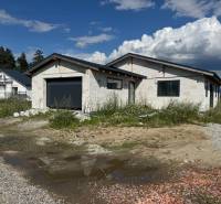 An unfinished family house in Valča with a garage, surrounded by nature and construction materials.