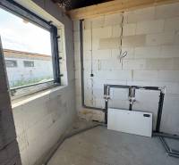 Unfinished room in a family house with concrete walls and a window.